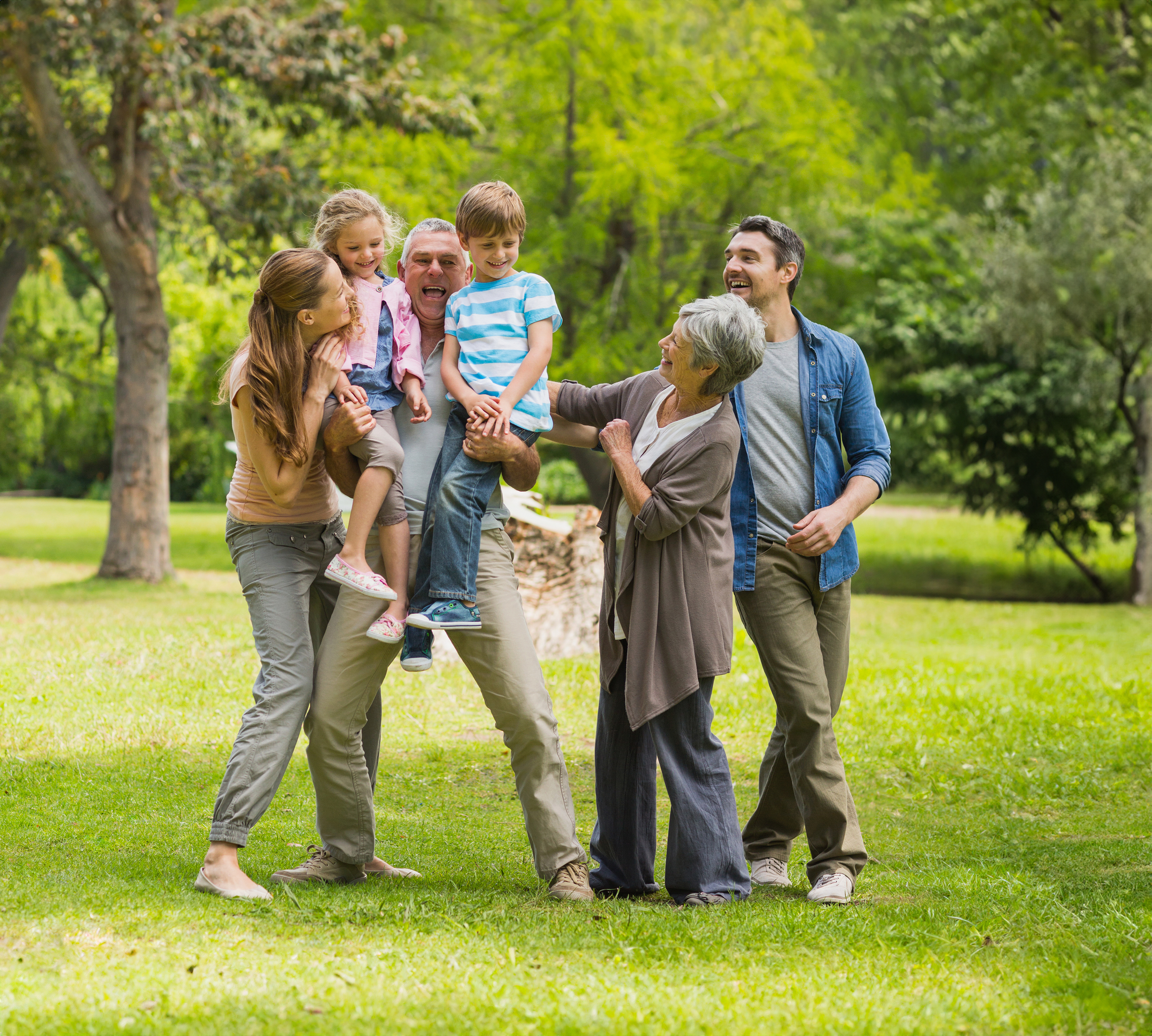 Eine Familie mit mehreren Generationen interagiert ausgelassen mitten im Grünen auf einer Wiese