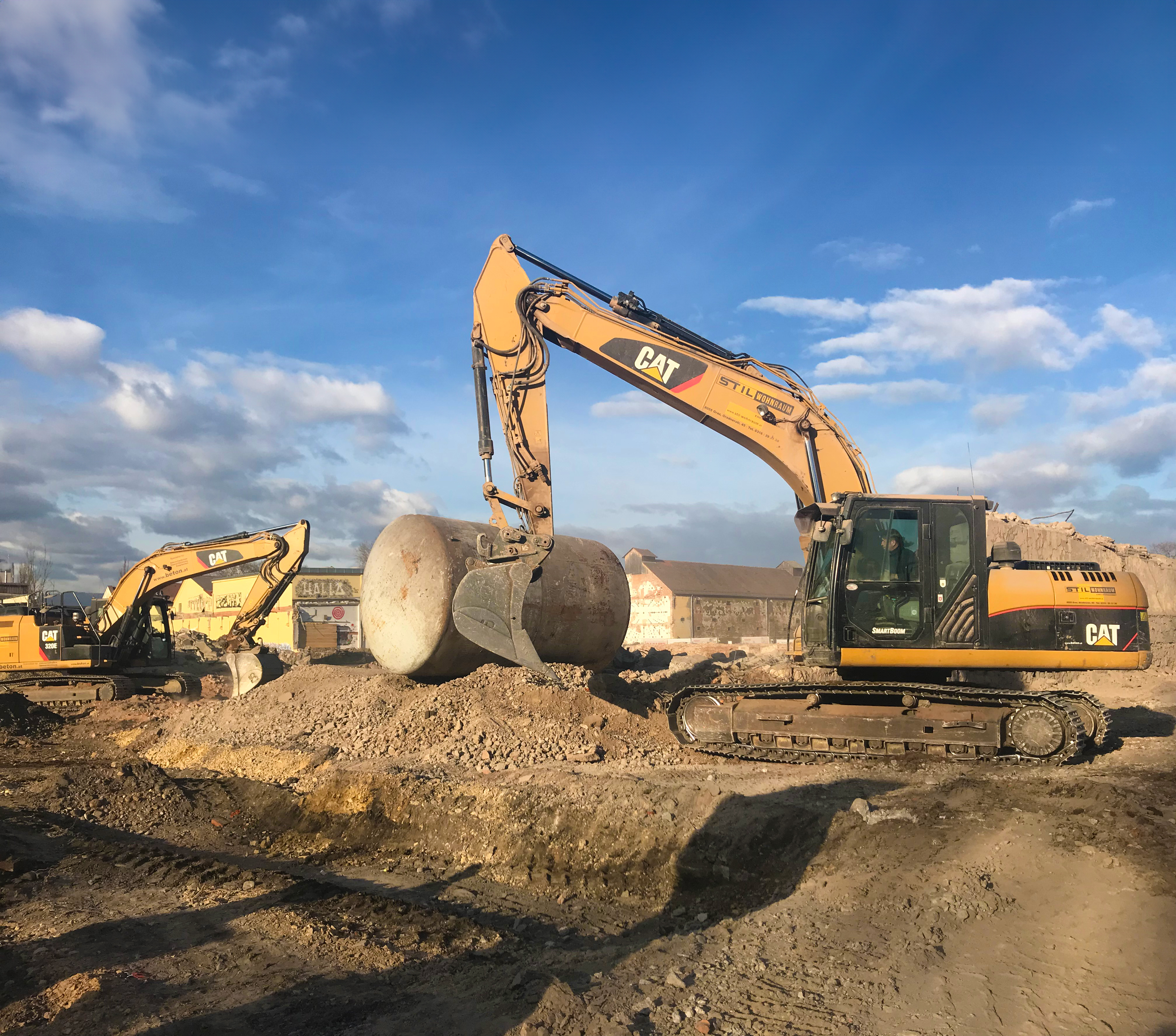 Ein Betonzylinder wird mit einem Bagger auf der großen Baustelle zusammengesetzt