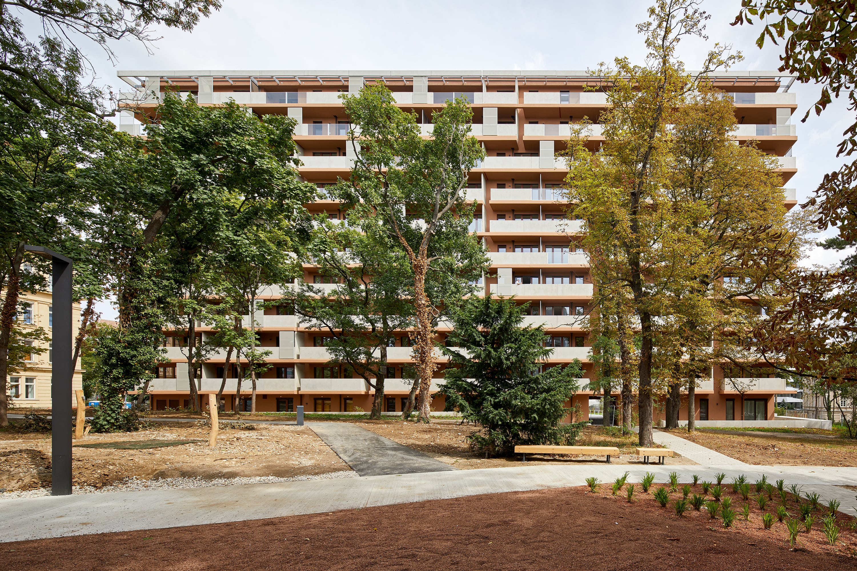 Außenansicht und Gesamtaufnahme von THEOS in 1140 Wien mit Bäumen vor dem Haus